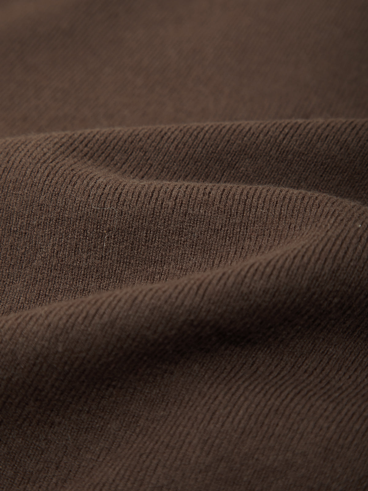 Close-up of a dark brown ribbed knit fabric with soft folds showing the texture and weave.