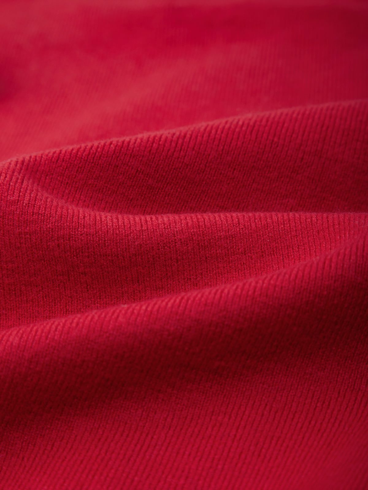 A close-up of red ribbed knit fabric with soft folds and a smooth texture.