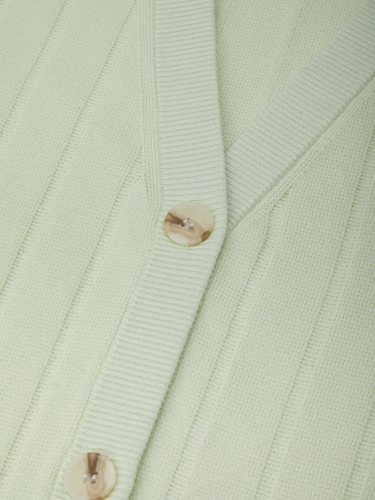 Close-up of a light green ribbed cardigan with button details