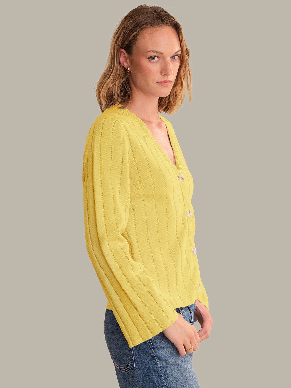 Woman wearing a yellow cardigan against a gray background