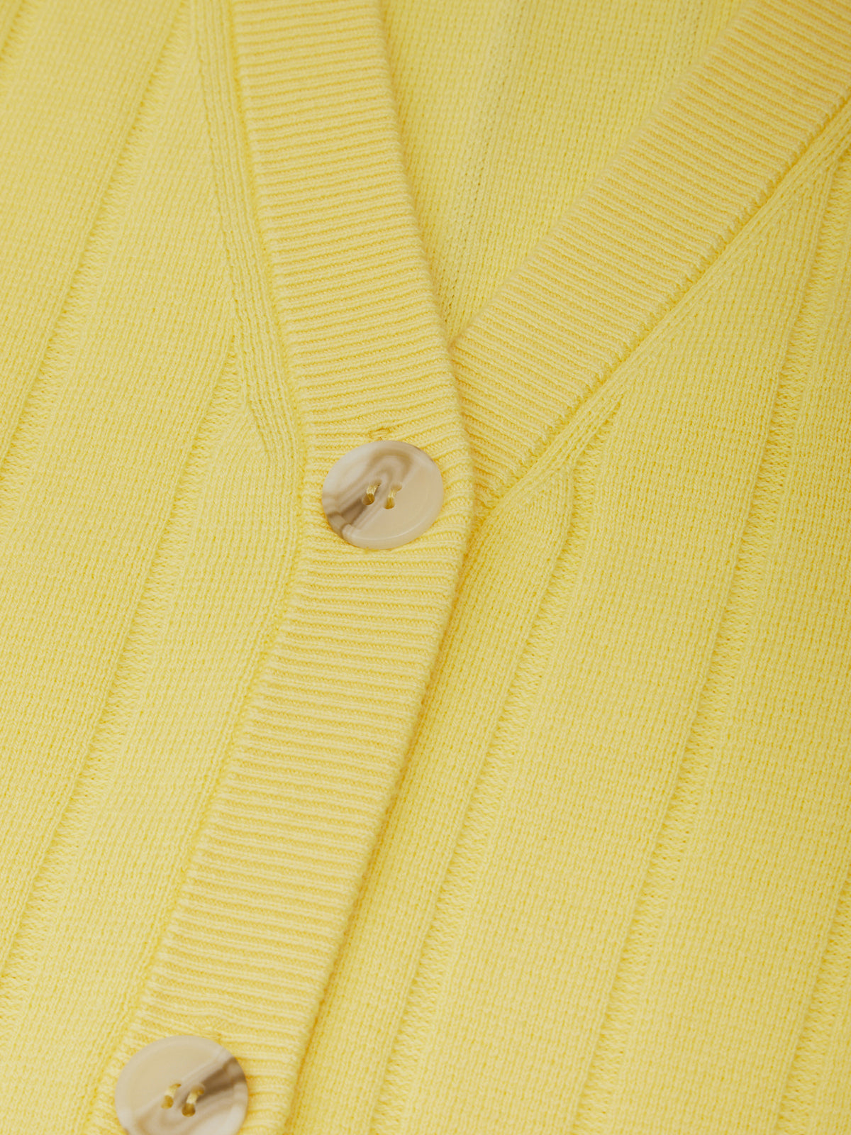 Close-up of a yellow textured fabric with buttons