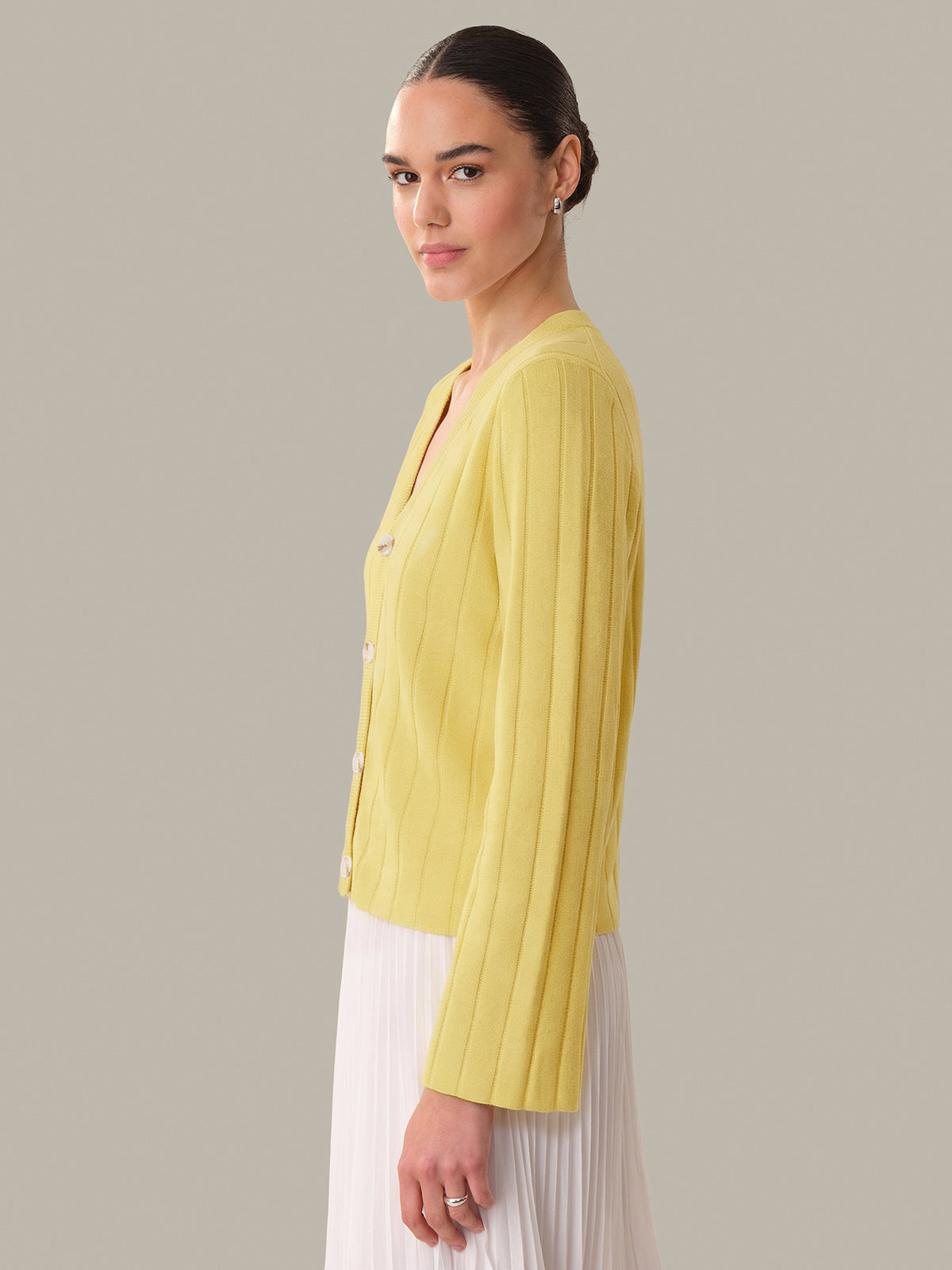 Woman wearing a yellow pleated blouse against a plain background