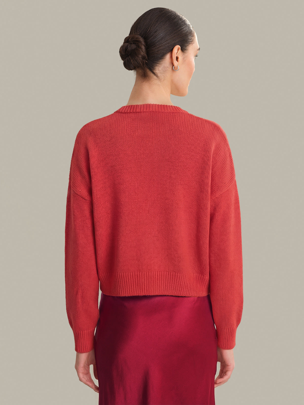 Woman wearing a red sweater and skirt against a neutral background