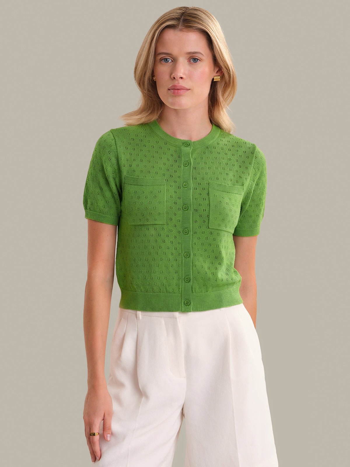 Woman wearing a green knitted top with a plain background