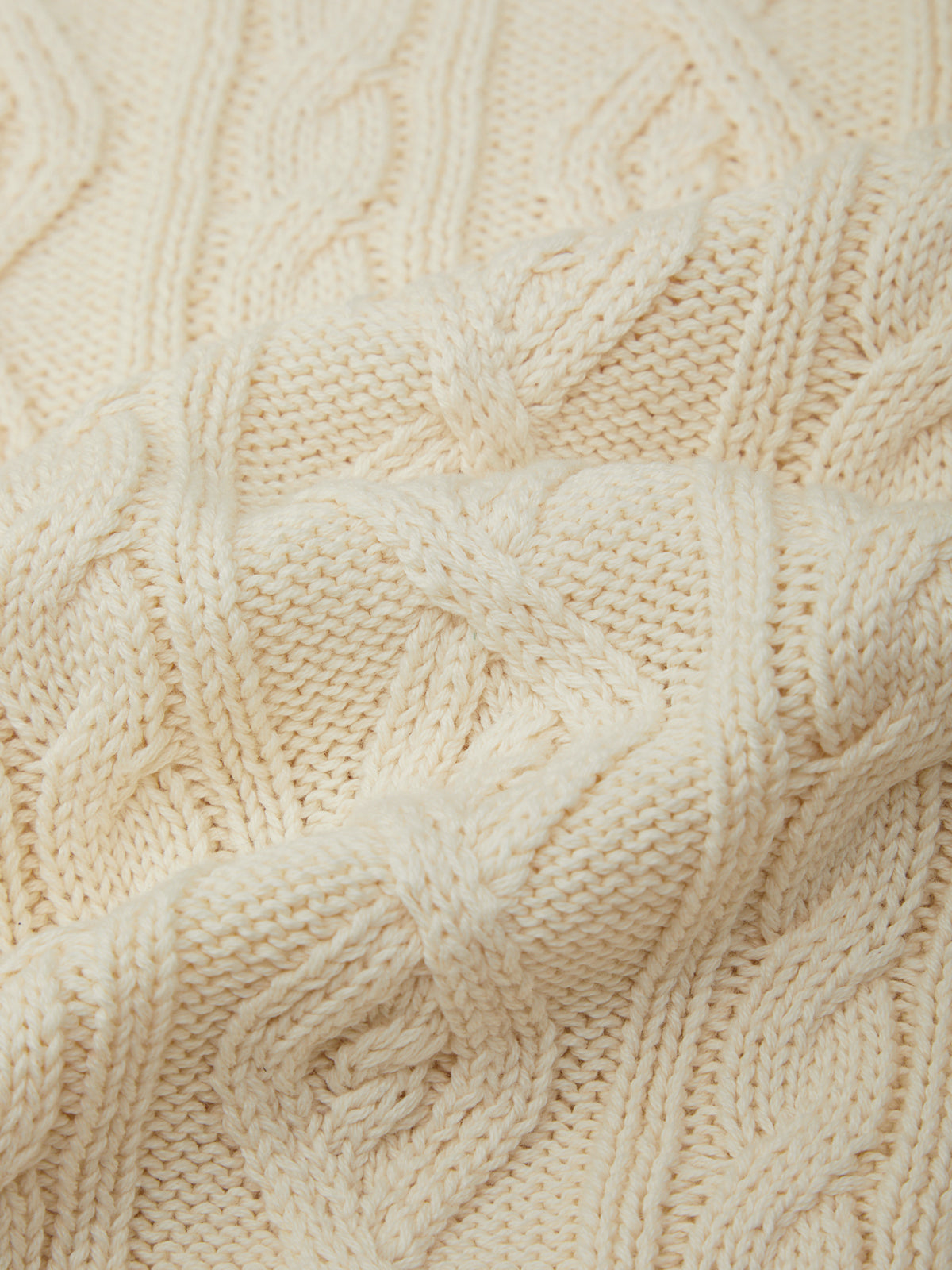 Close-up of a cream-colored knitted fabric with cable pattern