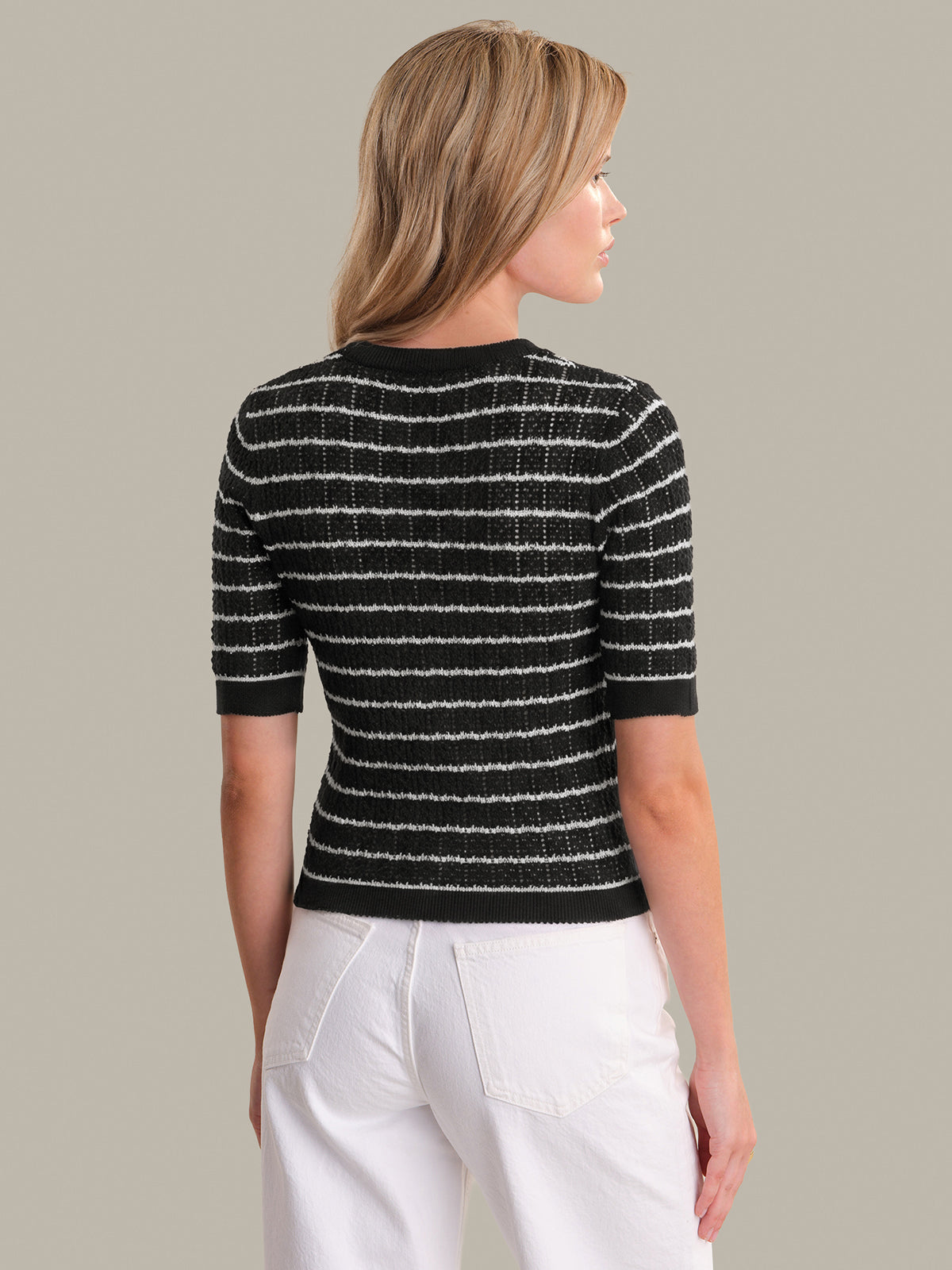 Woman wearing a black and white striped sweater against a neutral background