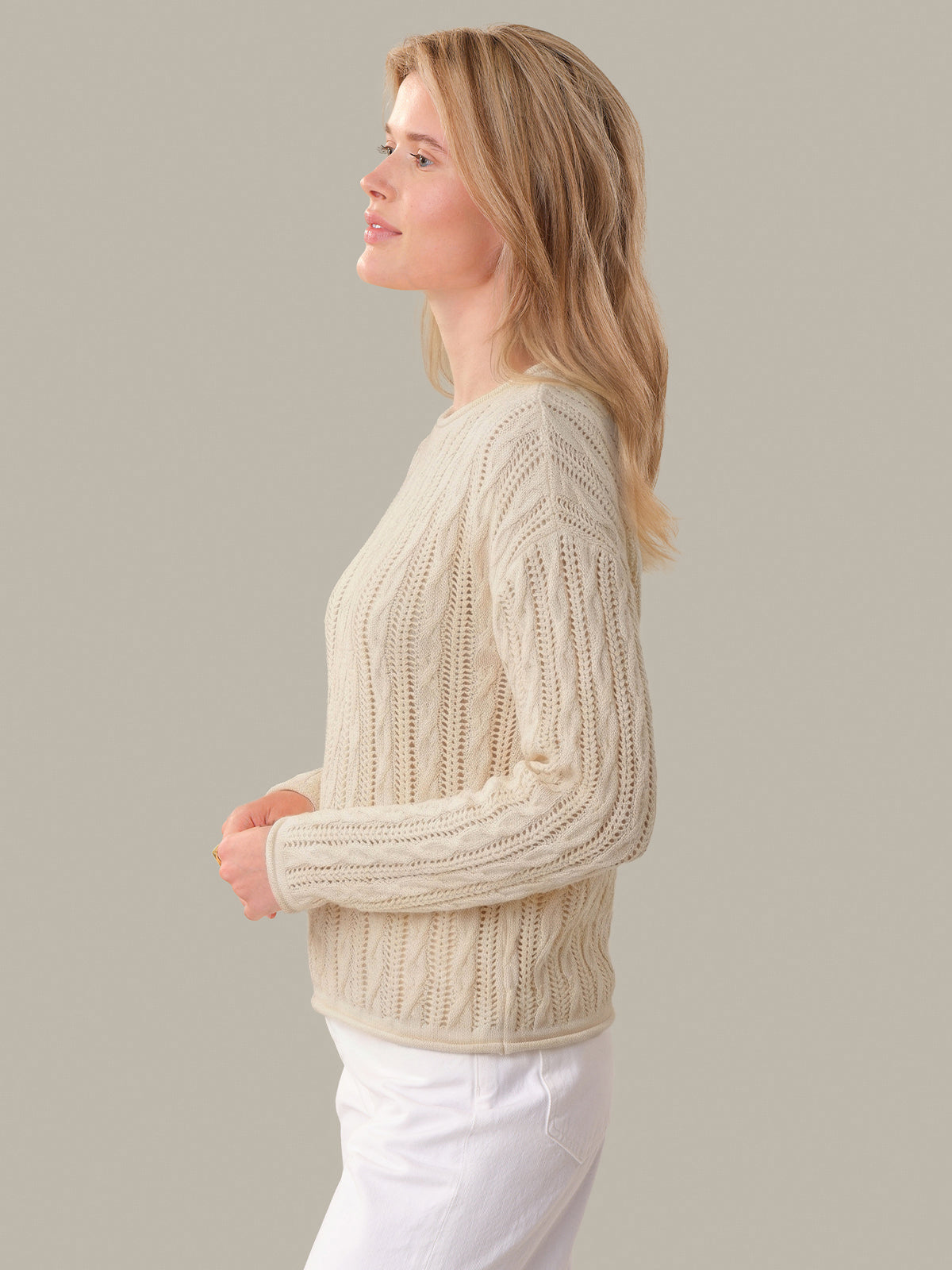 Woman wearing a beige knitted sweater against a plain background