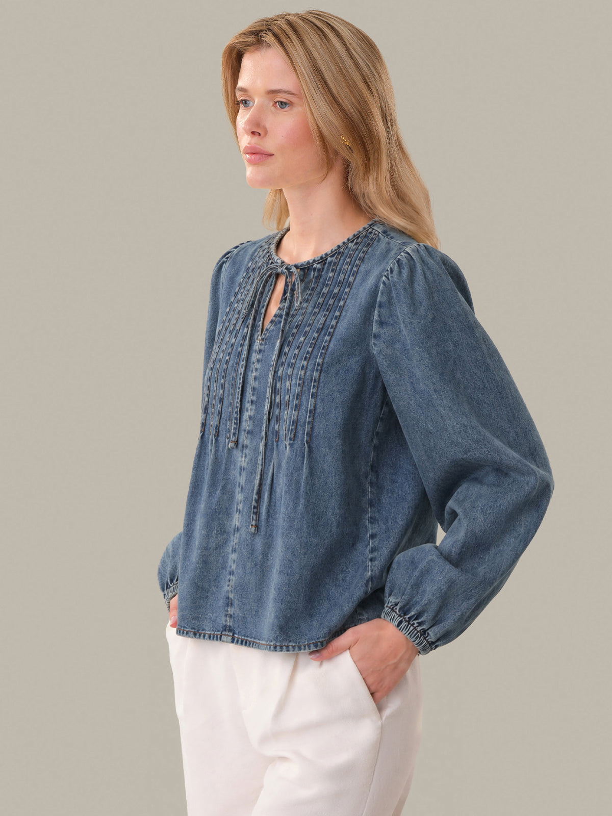 Woman wearing a blue denim blouse with long sleeves on a gray background