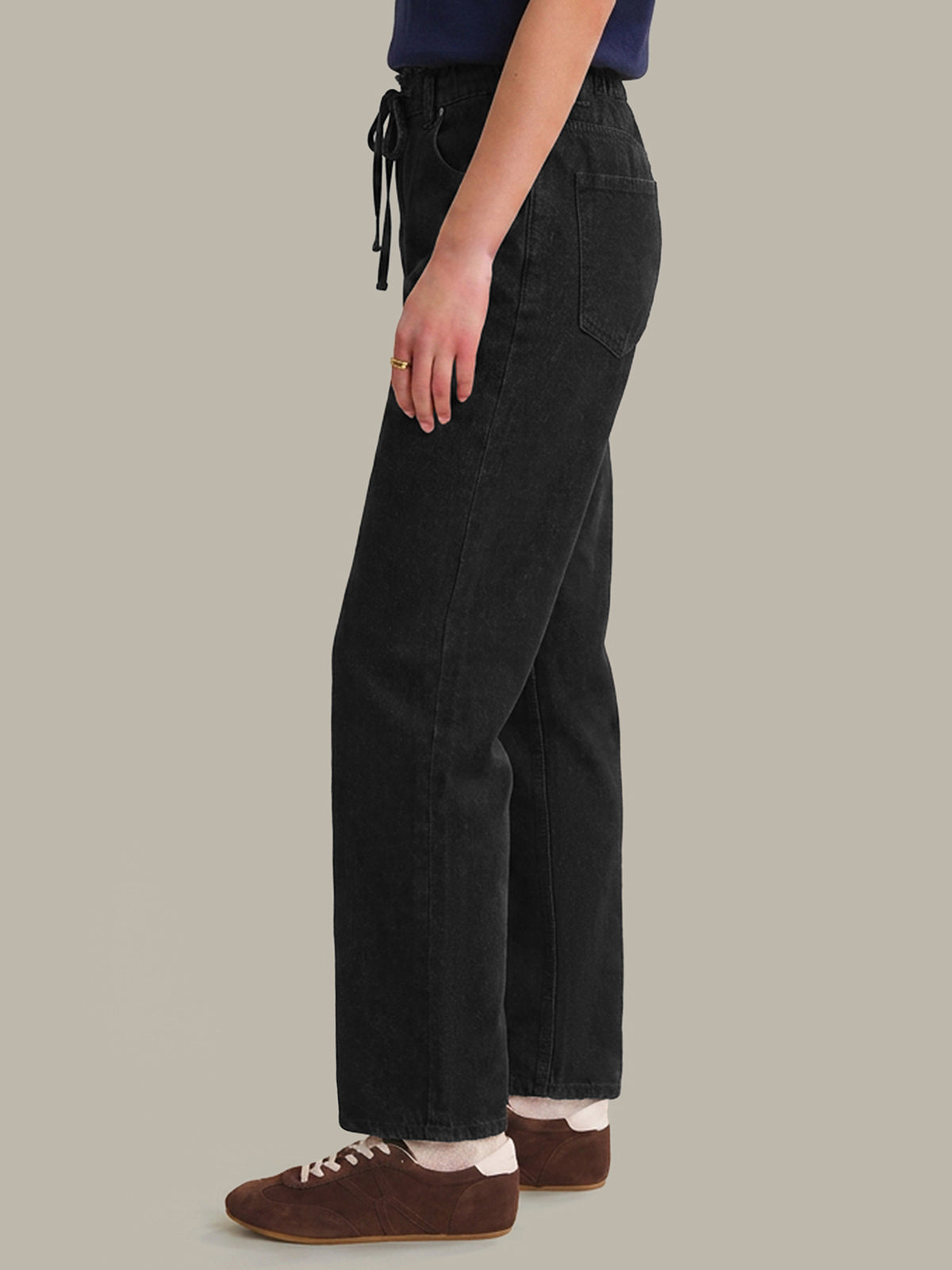 Person wearing black pants on a beige background