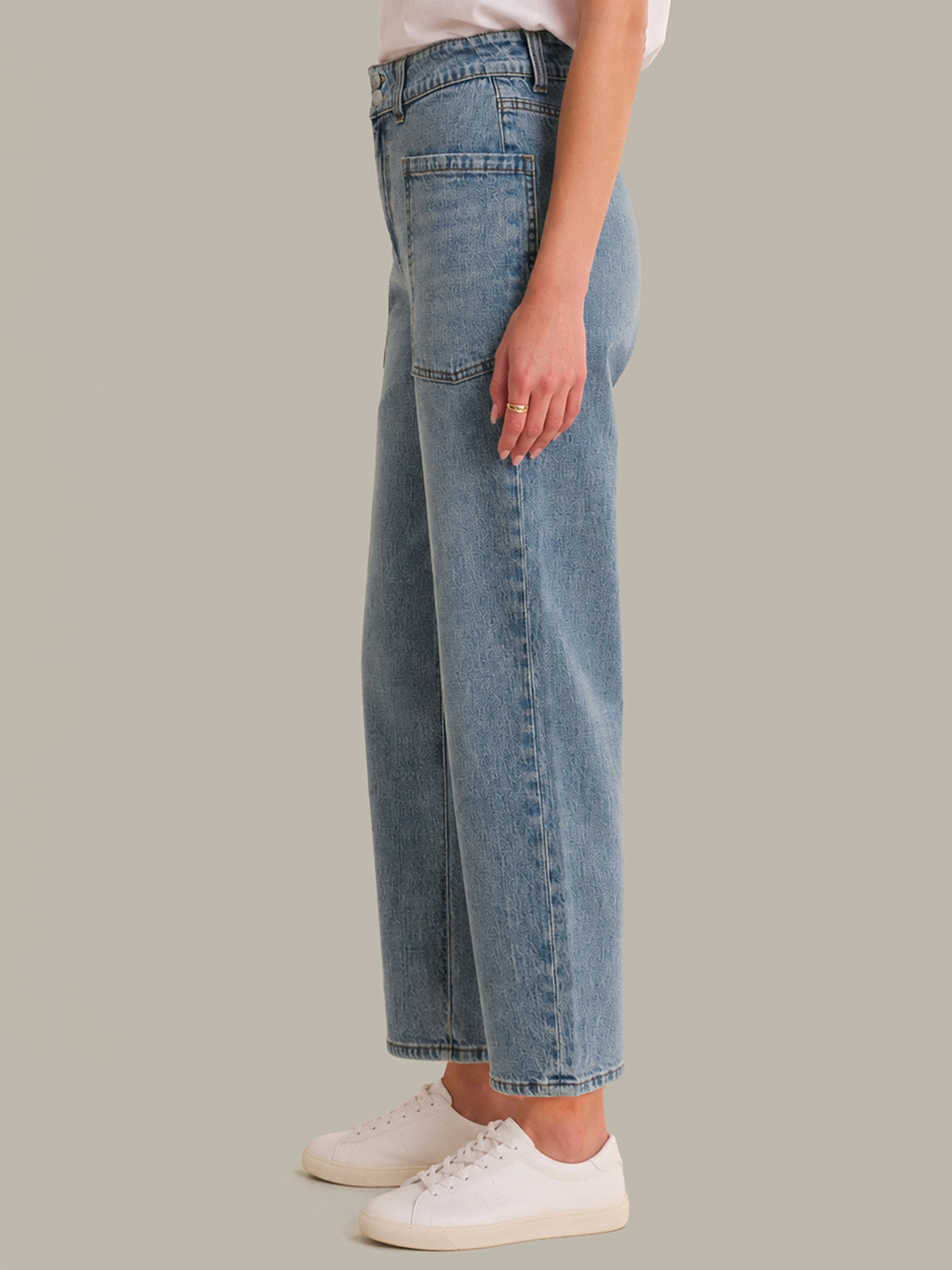 Person wearing blue jeans and white sneakers on a plain background