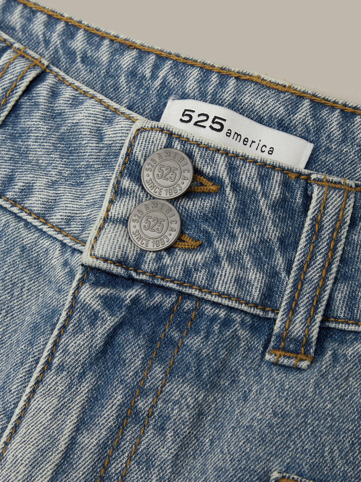 Close-up of blue jeans with a '525 America' label and coins on the pocket.