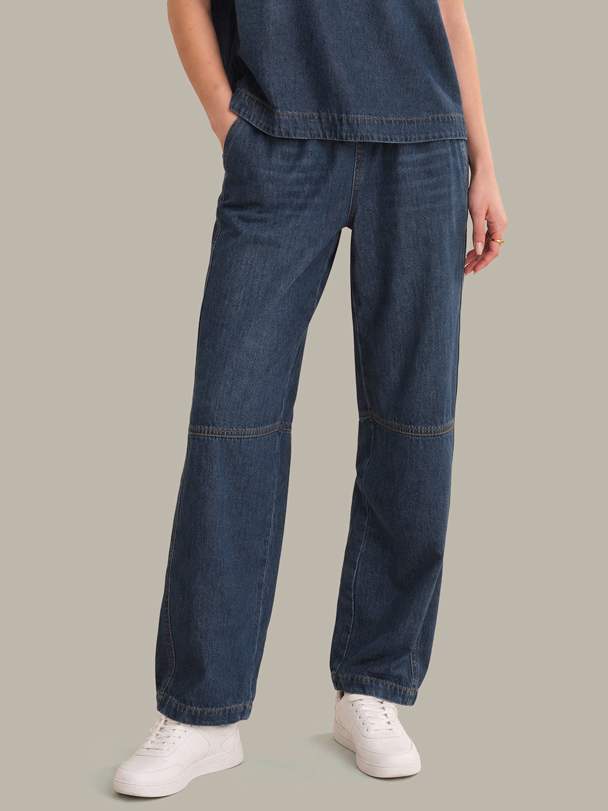 Person wearing blue jeans and white sneakers on a plain background
