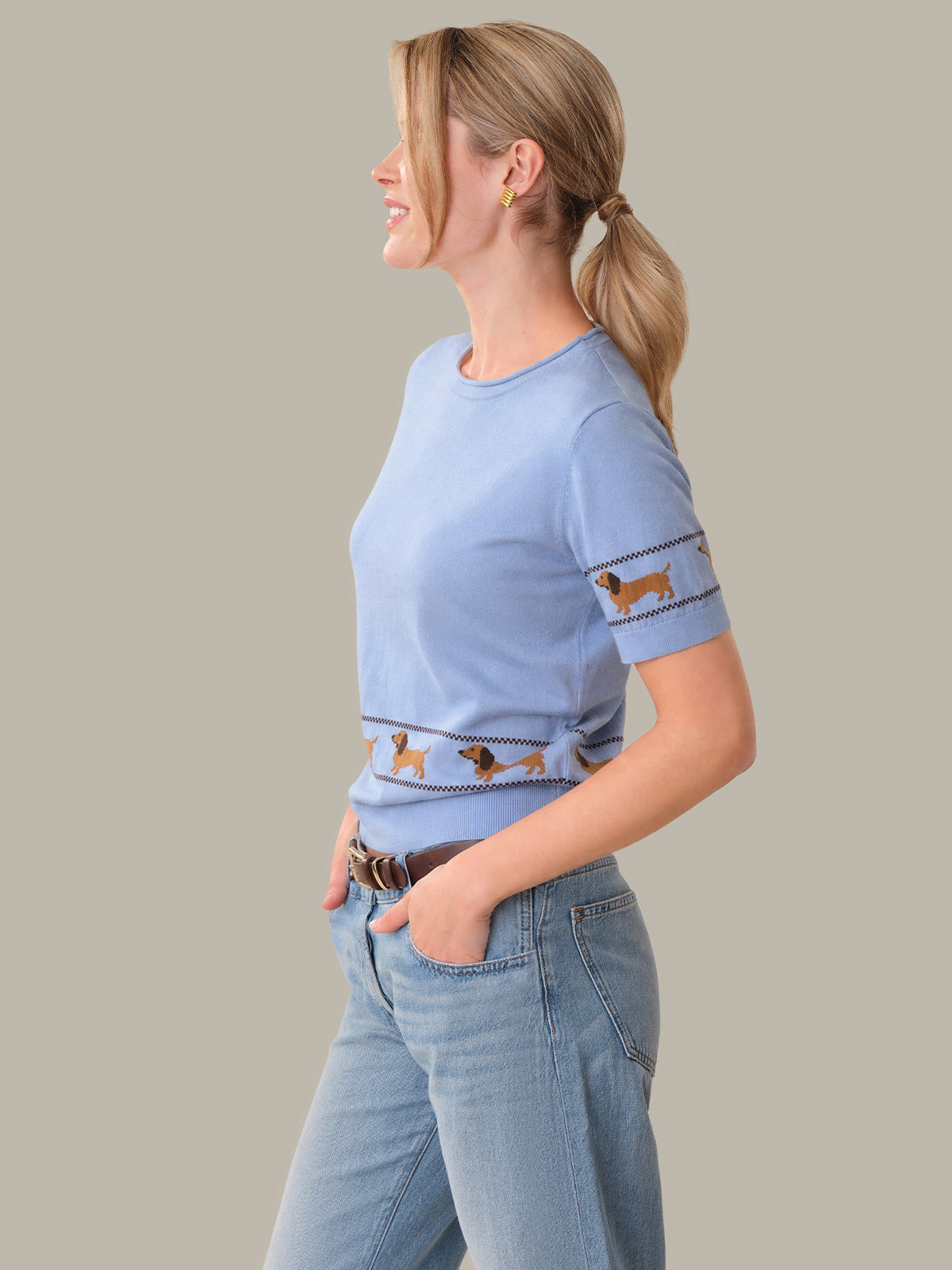 Woman wearing a light blue t-shirt with dog illustrations on a plain background