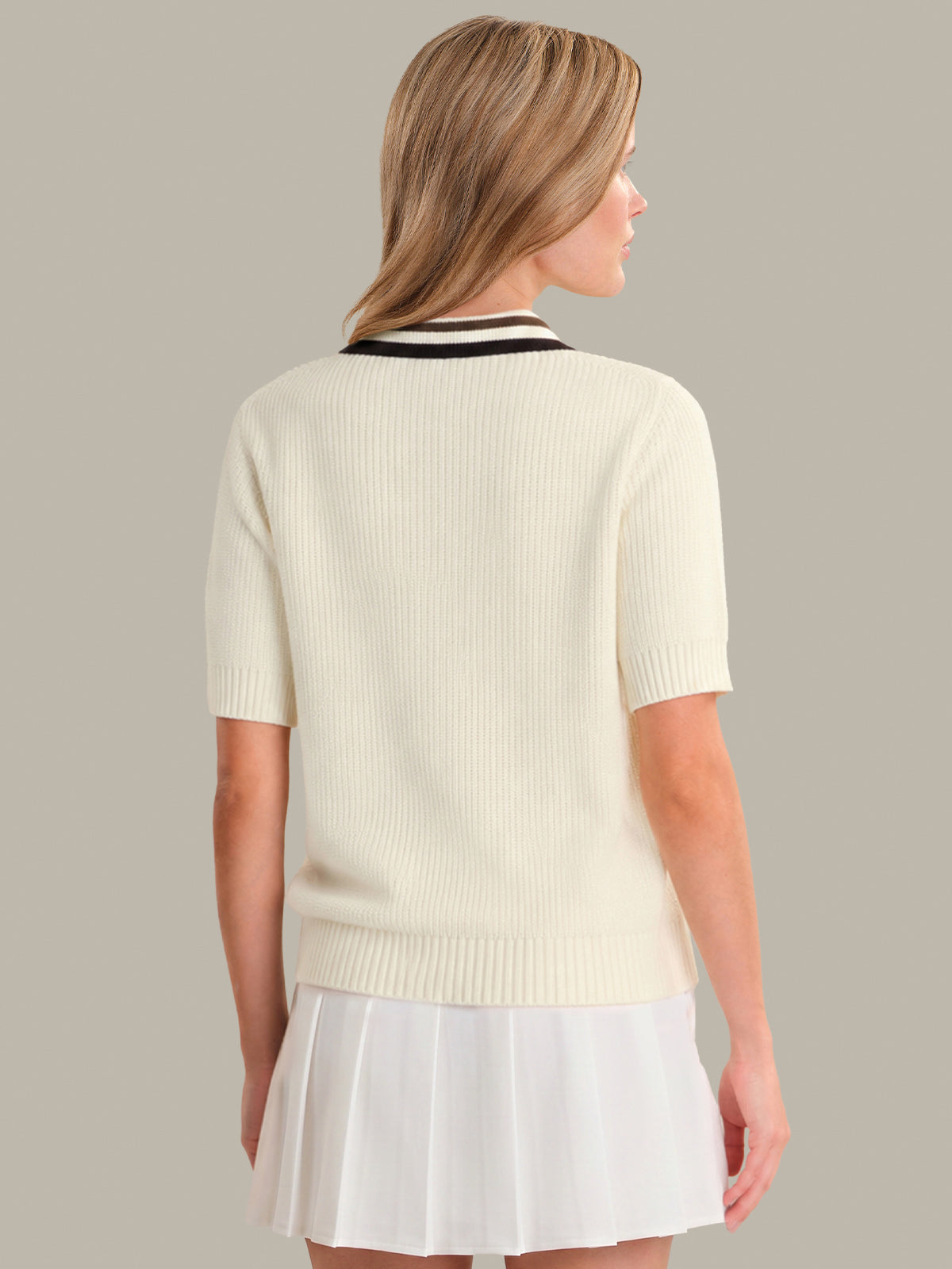 Woman wearing a cream-colored sweater with a black collar against a neutral background