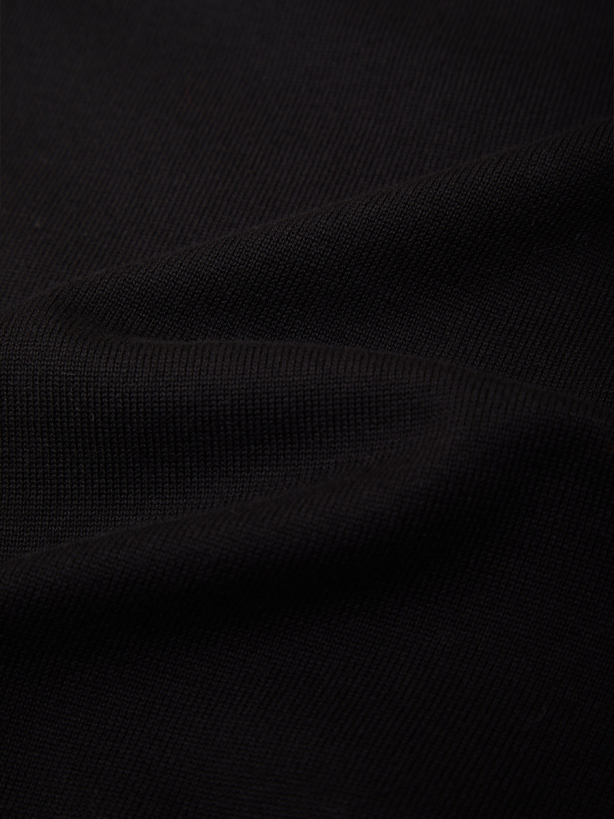 A close-up of black textured fabric with soft folds and a fine woven pattern.