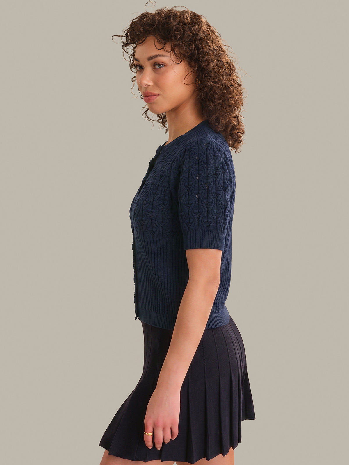 Woman wearing a navy blue knitted top and skirt on a gray background