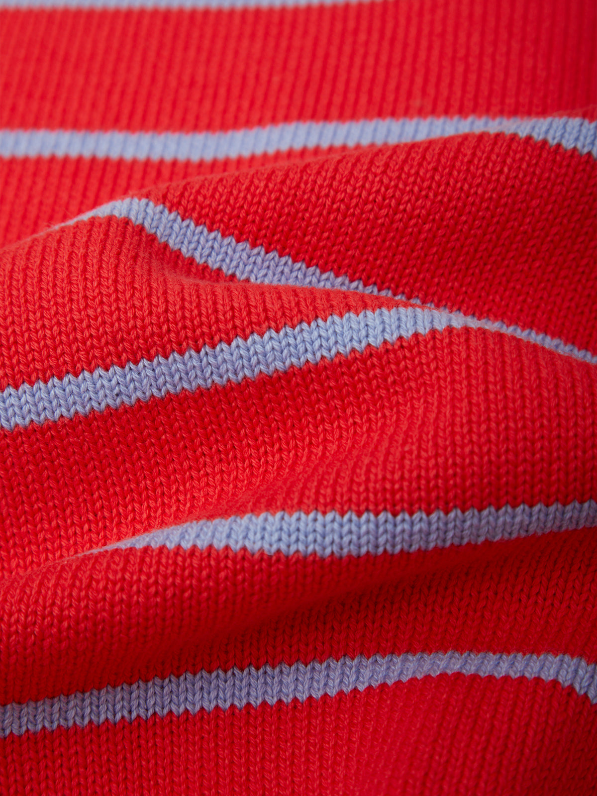 A close-up of a red knit fabric with thin light blue horizontal stripes.