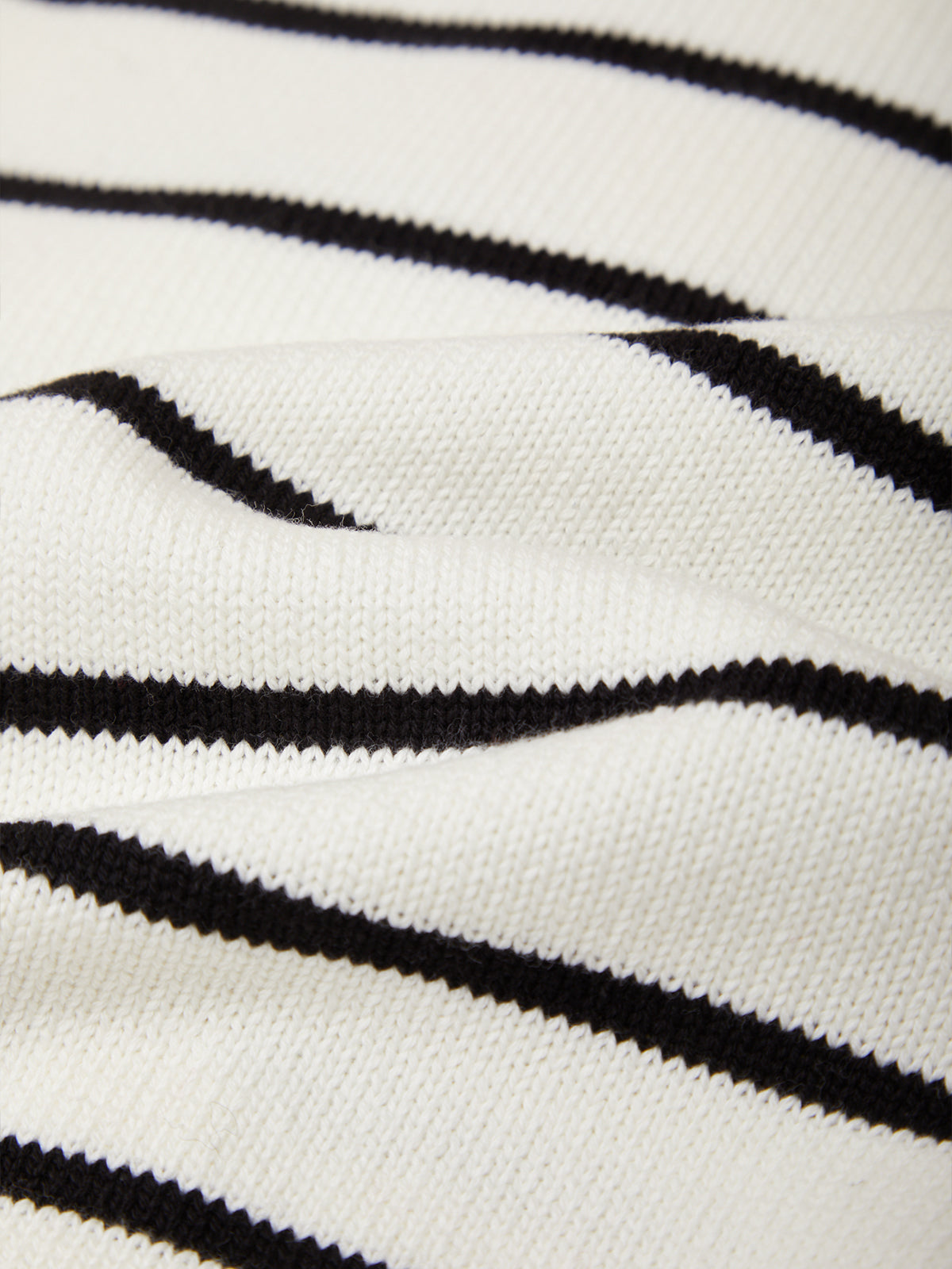 Close-up of a knit fabric with a black and white striped pattern, showing the texture and weave.
