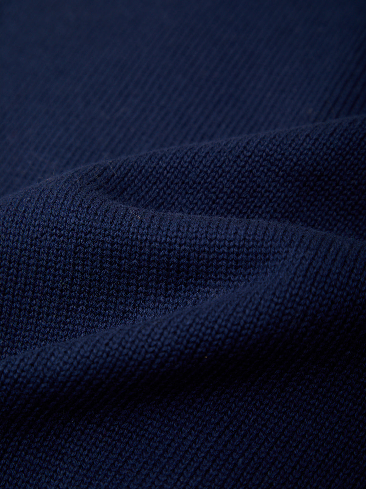 Close-up of dark navy blue knit fabric with a ribbed texture and soft folds.