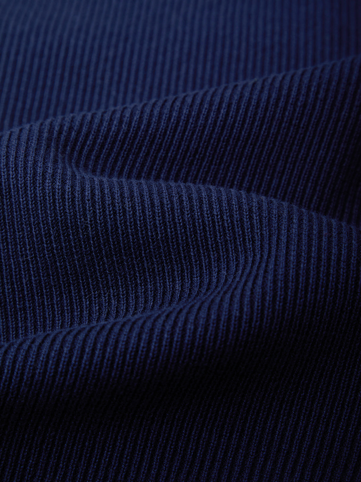 A close-up of dark navy blue ribbed knit fabric with soft folds showing the texture and weave.