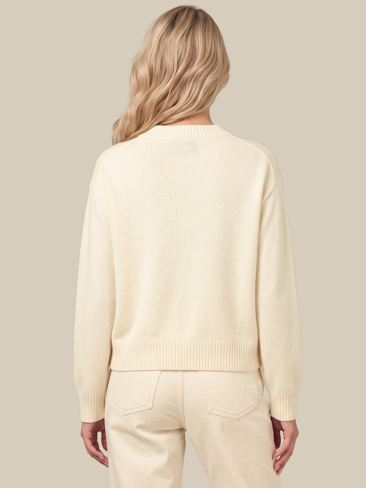 A woman shown from the back wearing a cream-colored knit sweater and matching cream pants against a solid beige background.