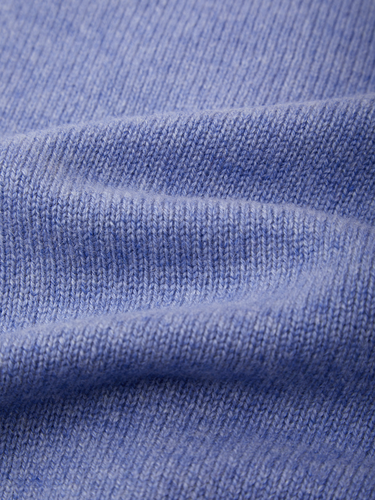 A close-up of a light periwinkle blue knit fabric, showing the detailed ribbed texture and soft folds.