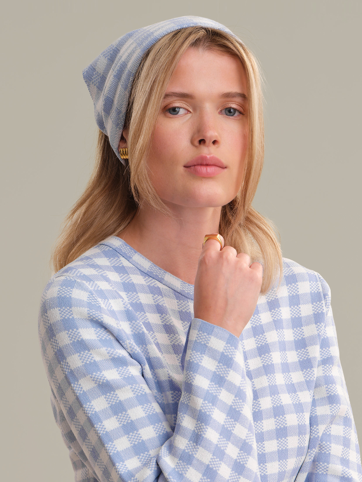 Woman wearing a blue and white checkered outfit with a matching beanie against a neutral background