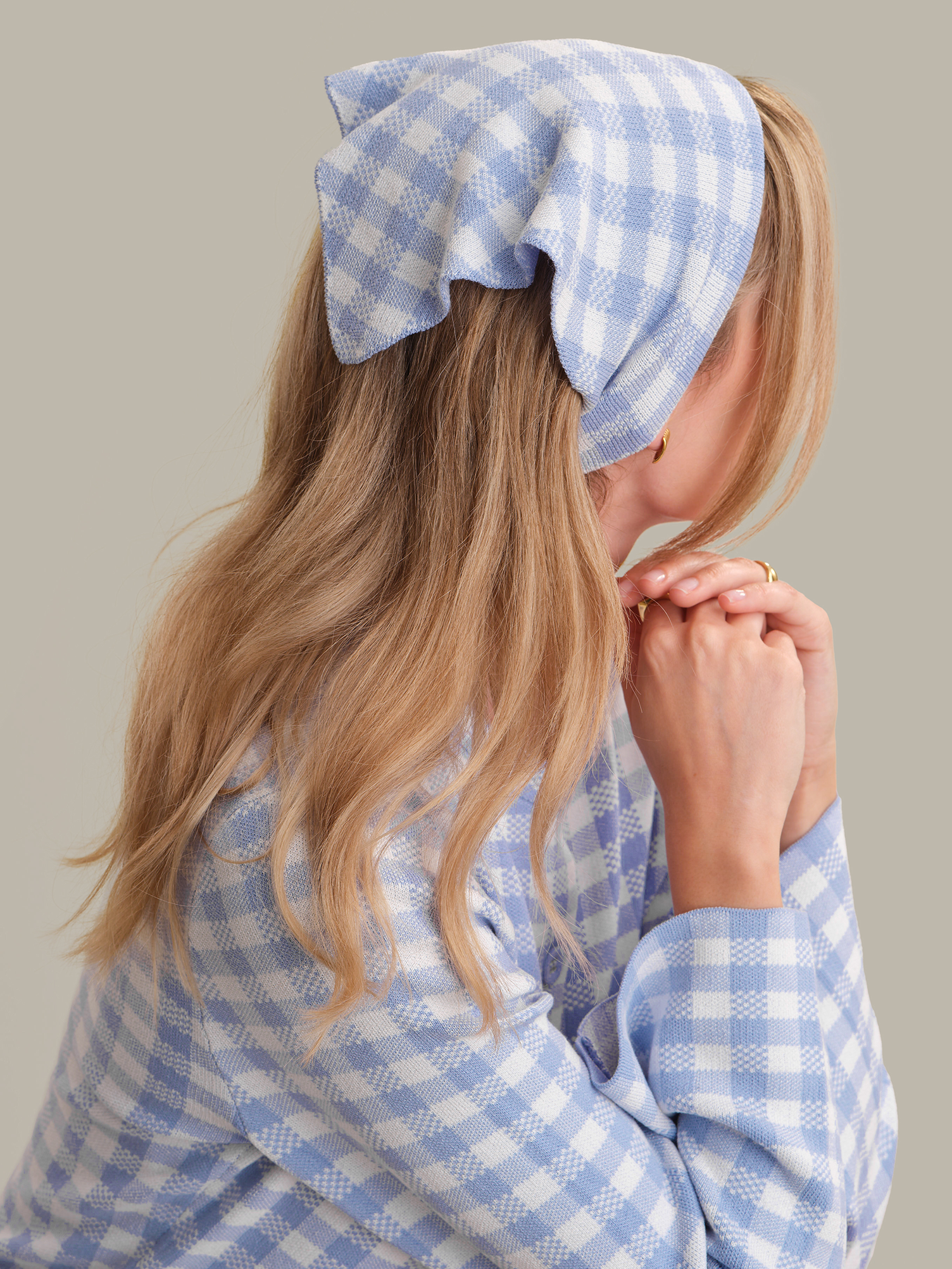 Person wearing a blue and white checkered headband and shirt against a neutral background