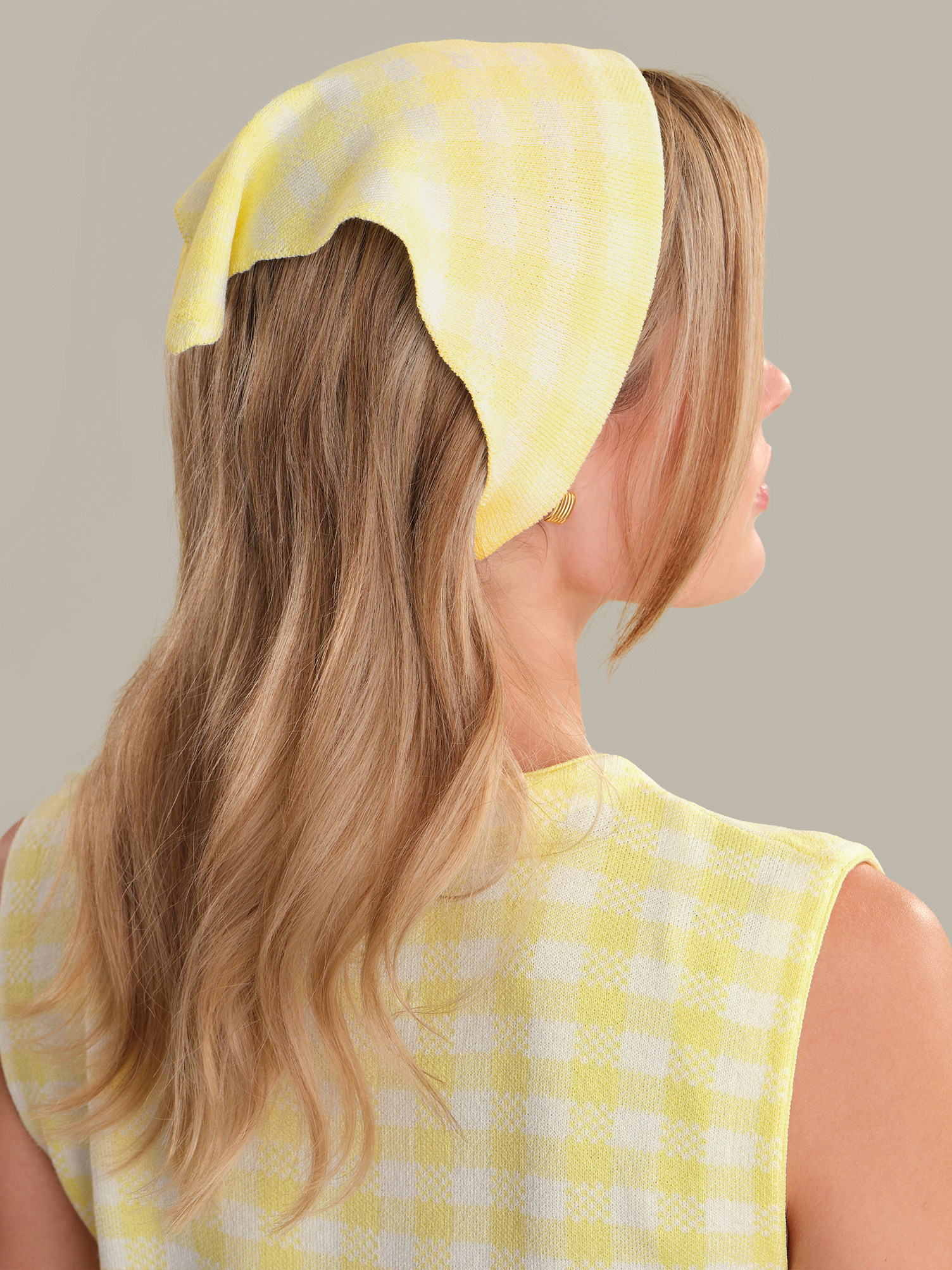 Woman wearing a yellow polka dot headscarf on a gray background
