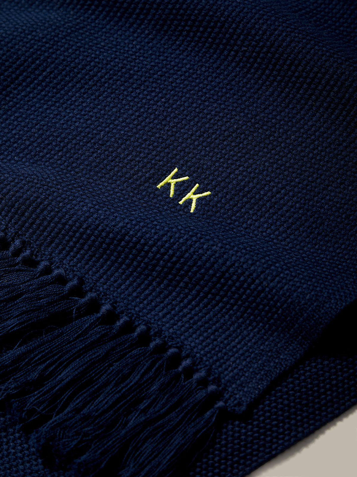 Navy blue scarf with yellow embroidered initials on a neutral background
