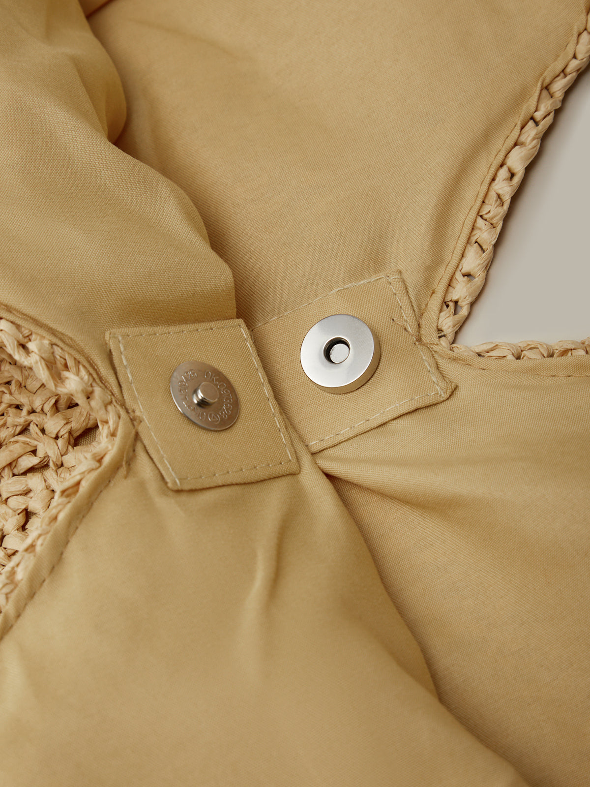 Close-up of a beige jacket with textured trim and button details.