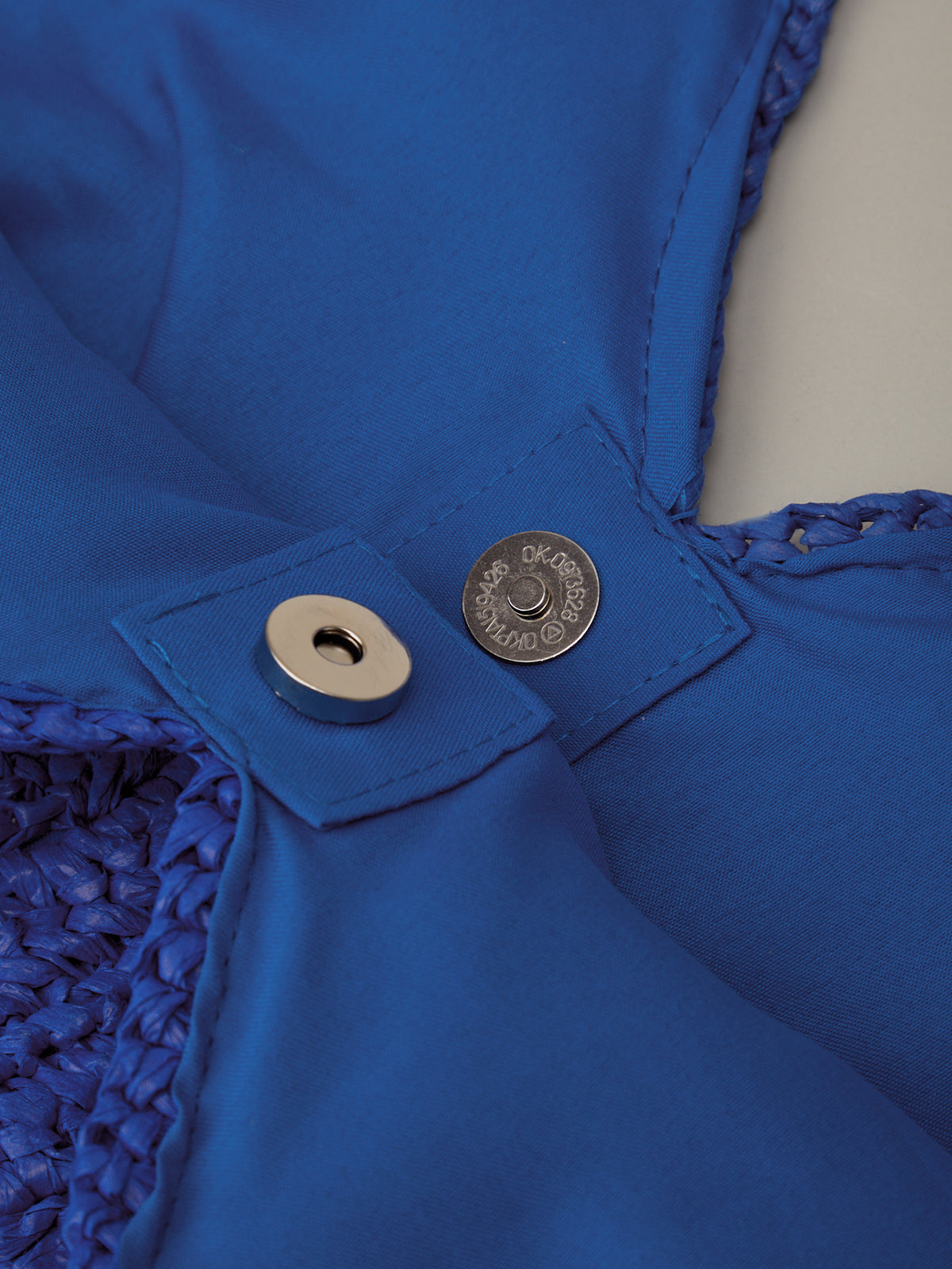 Close-up of a blue fabric with a button and metal component.