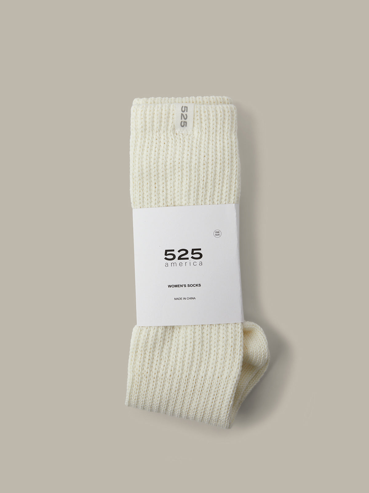 Pair of white socks with a visible brand label on a beige background
