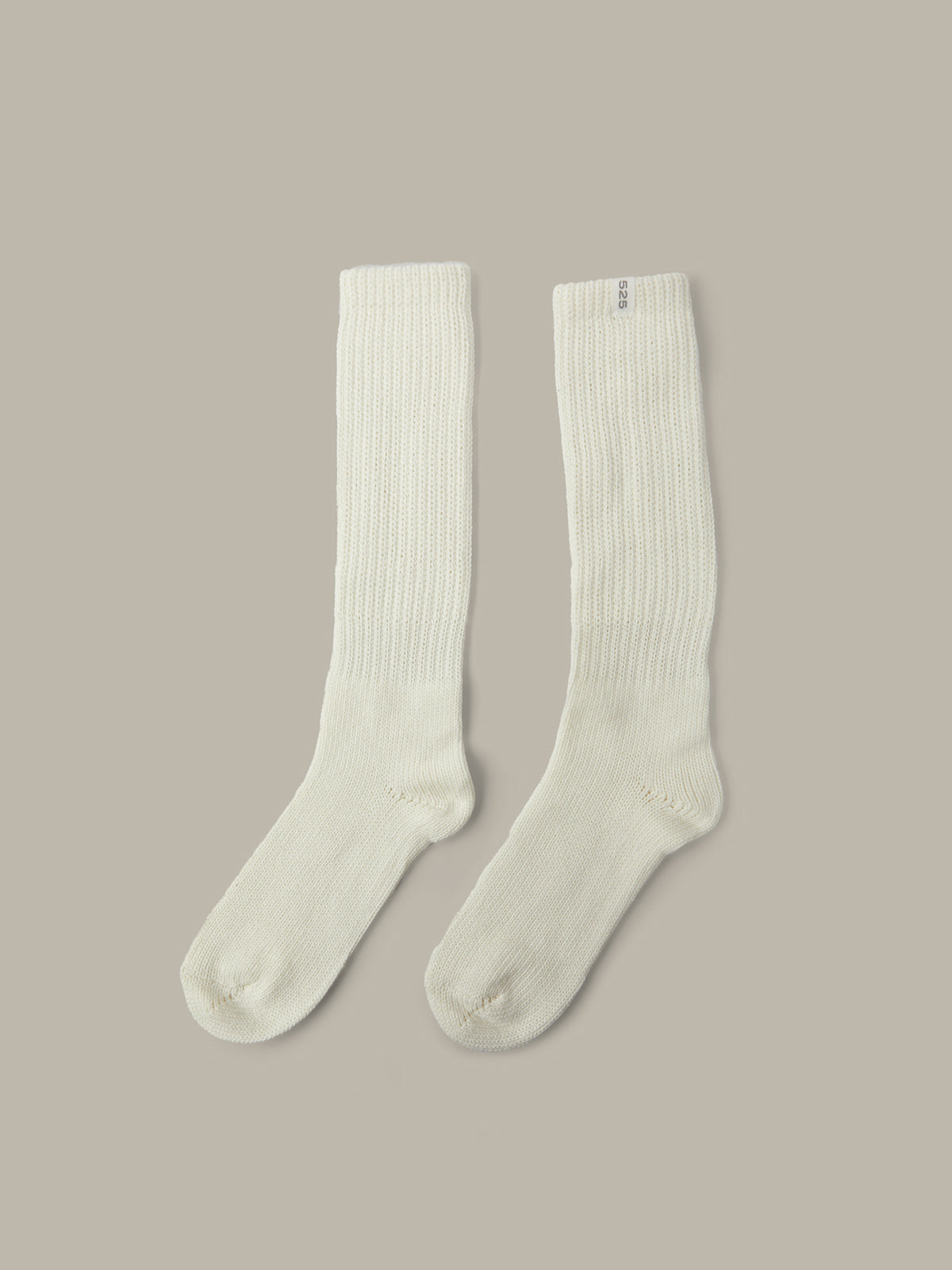 Pair of white knee-high socks on a beige background