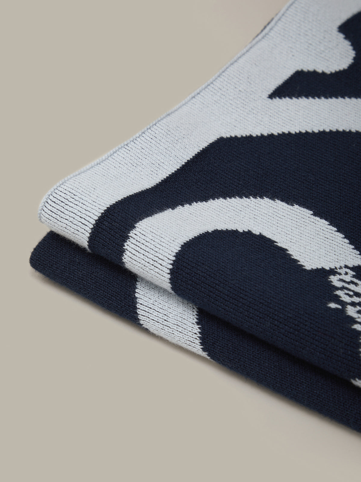 Stack of navy and light gray patterned socks on a beige background