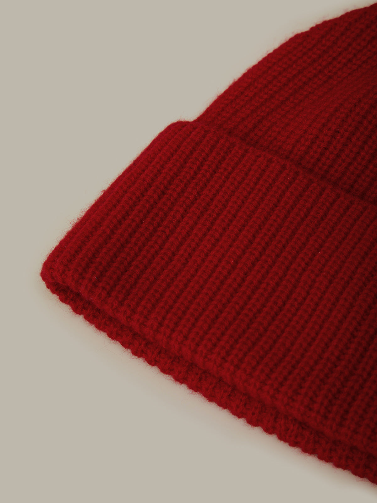 Close-up of a red knitted beanie on a beige background