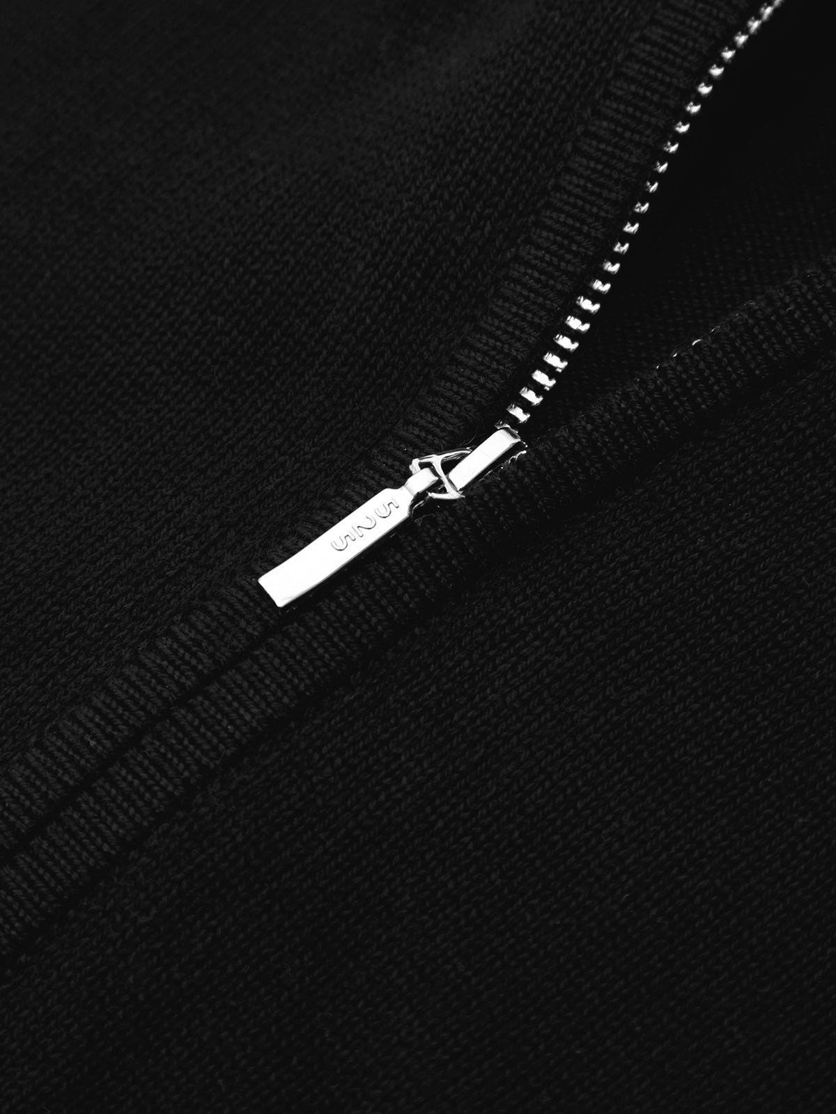 Close-up of a silver zipper on a black background
